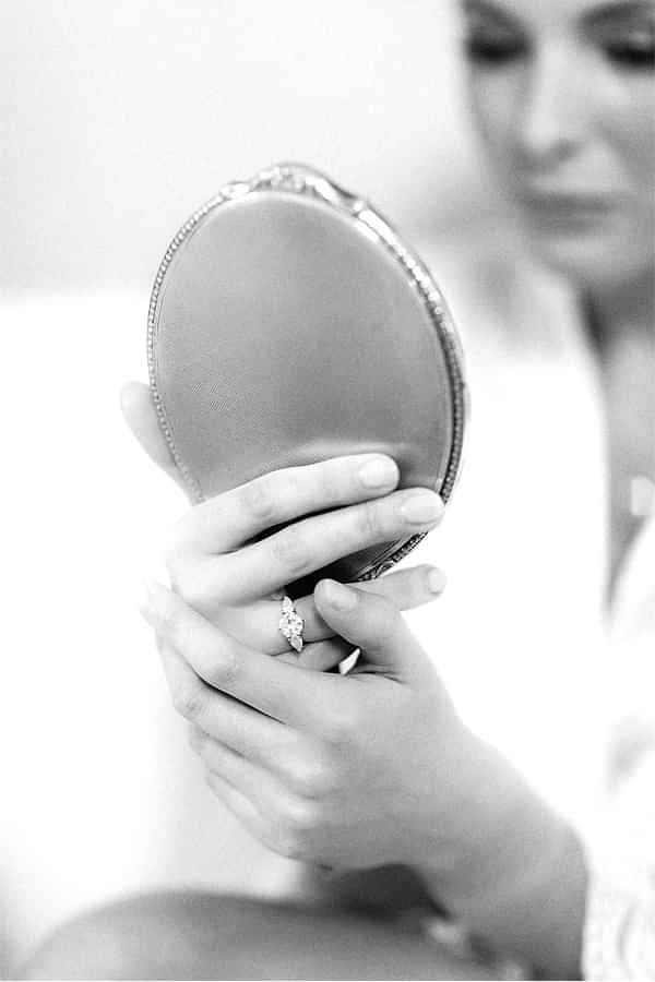 bride looking at a mirror with engagagment ring