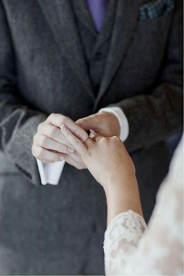 groom puting a wedding ring on bride