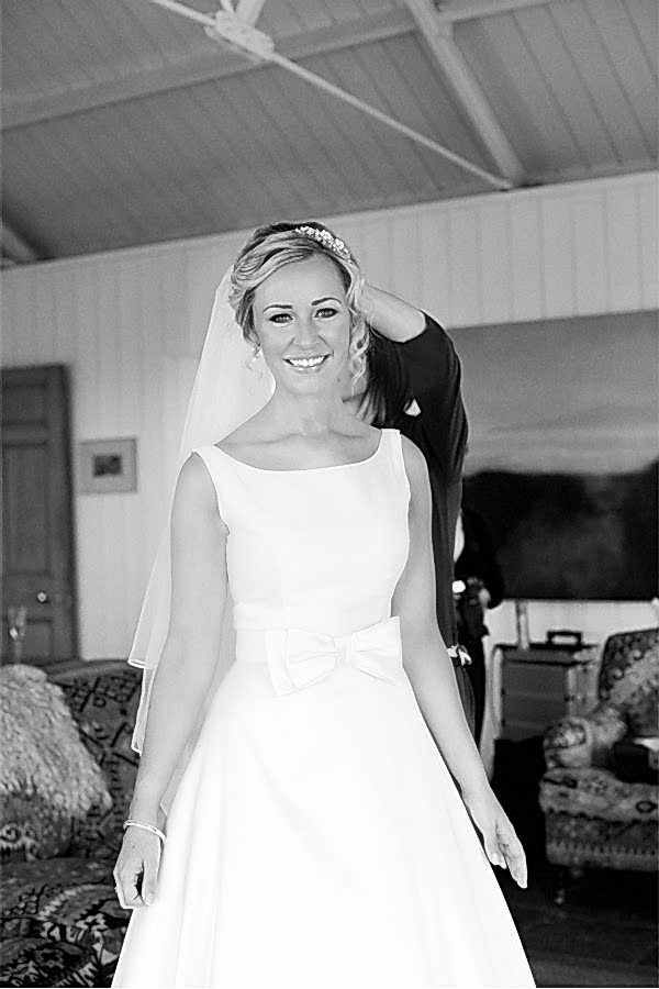 bride looking at photographer having her veil fixed