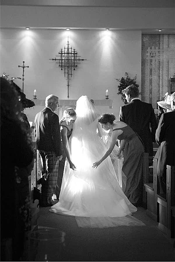 bride having her dress and veil fixed at church ceremony