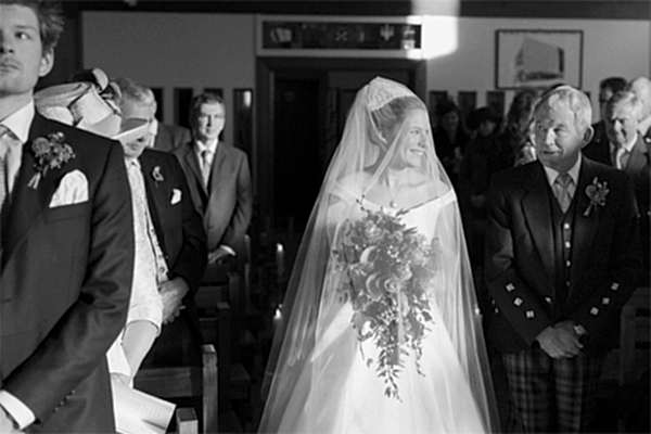 bride smiling to her father while walking down the aisle
