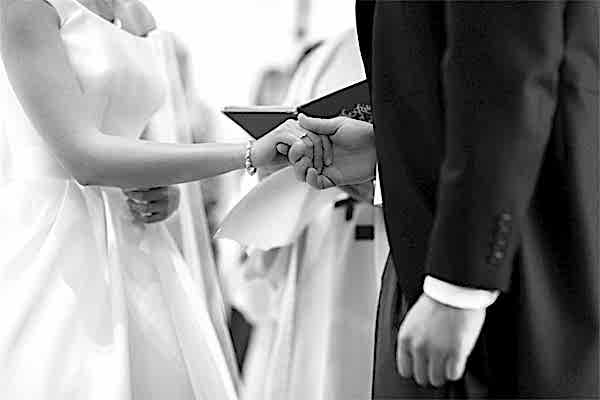 bride and groom holding their hands during roman catholic ceremony