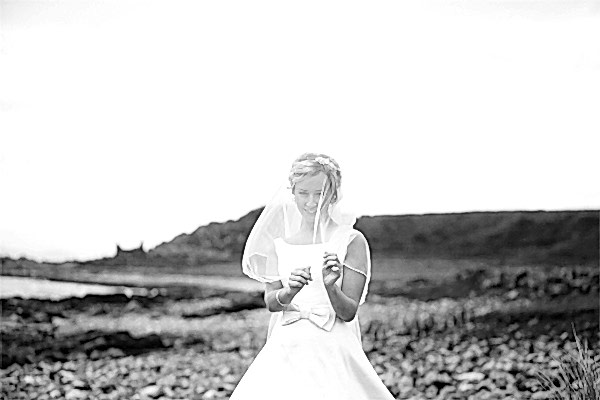 bride playing with his veil on a beach