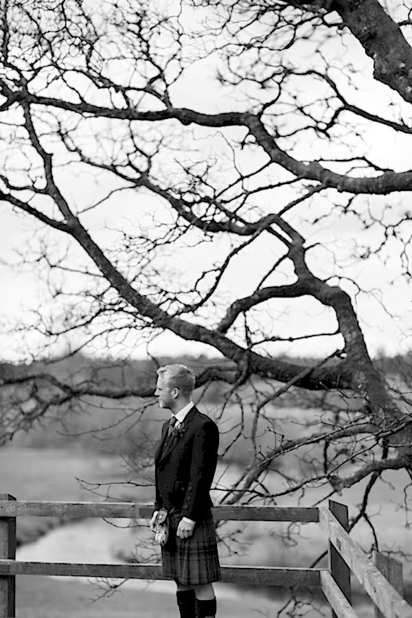 groom standing next to big tree