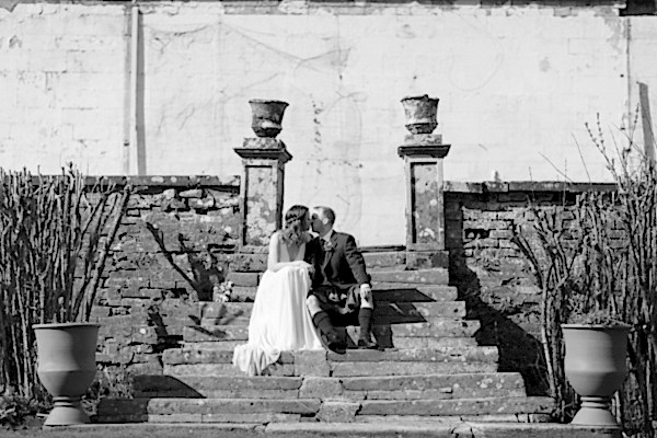 bride and groom sitting and kissing at a garden