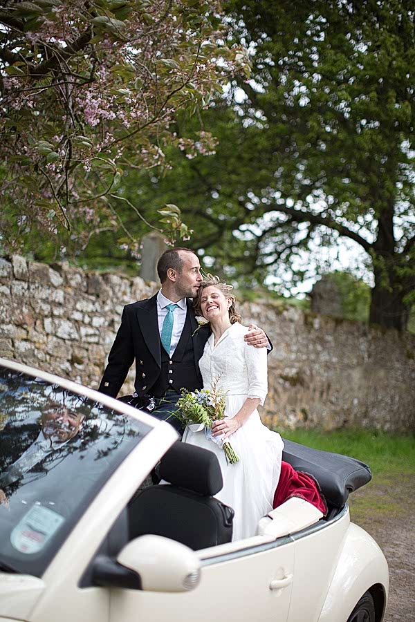 bride and groom huging driving away in a car