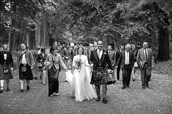wedding party walking through the forest at oxenford castle in scotland