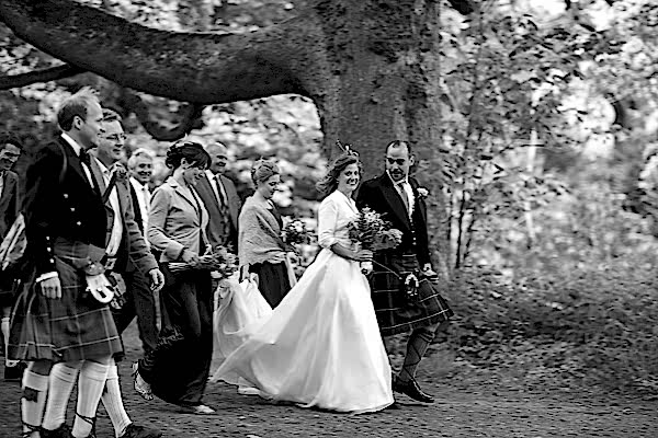 bride and groom walking with thier guests to ther wedding venue