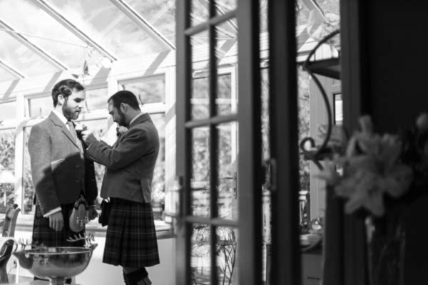 groom having his button whole fixed by best man