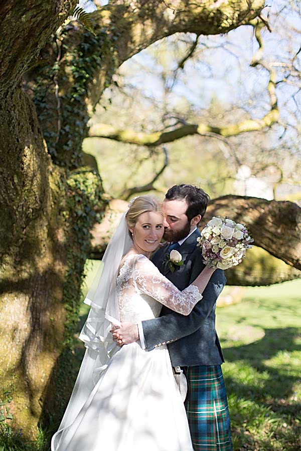 newlyweds embraced under a large tree at boturich castle gardens