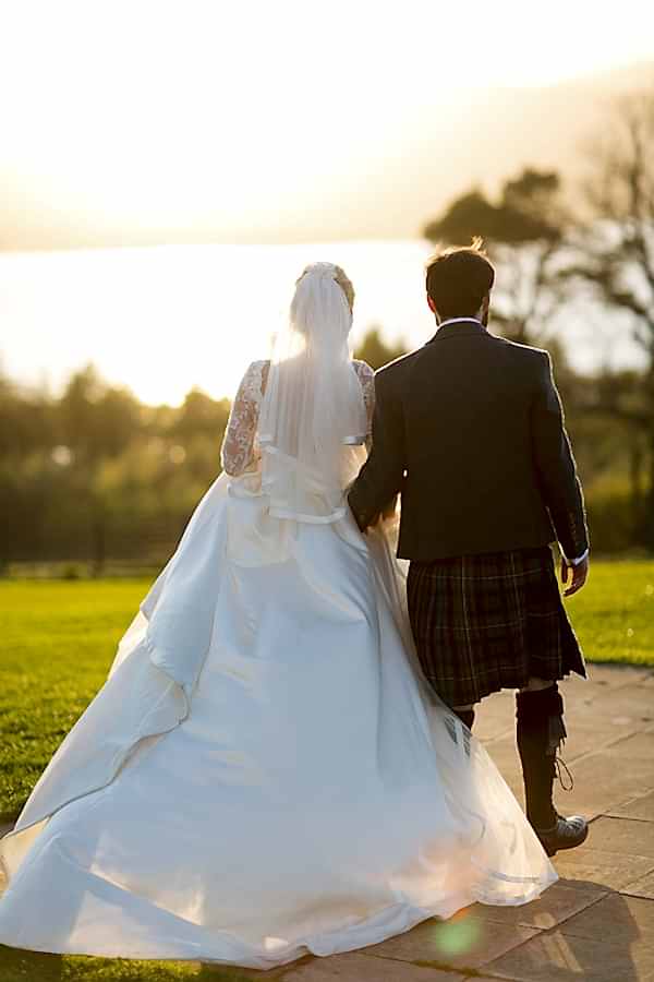newlyweds walking away towards loch lomond and sunset