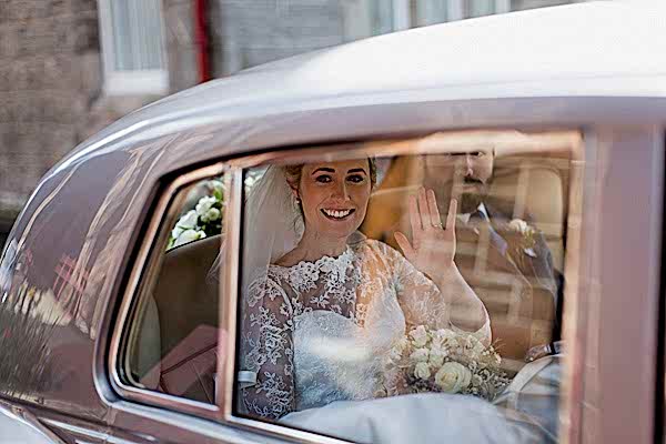 bride waving to teh guests leaving