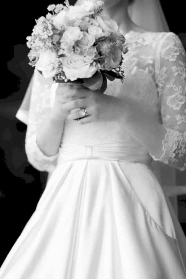 bride holding flowers, wedding ring visible