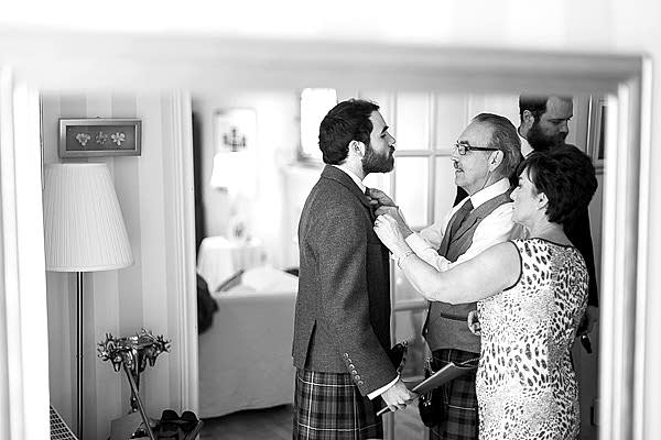 groom having his tie fixed by parents