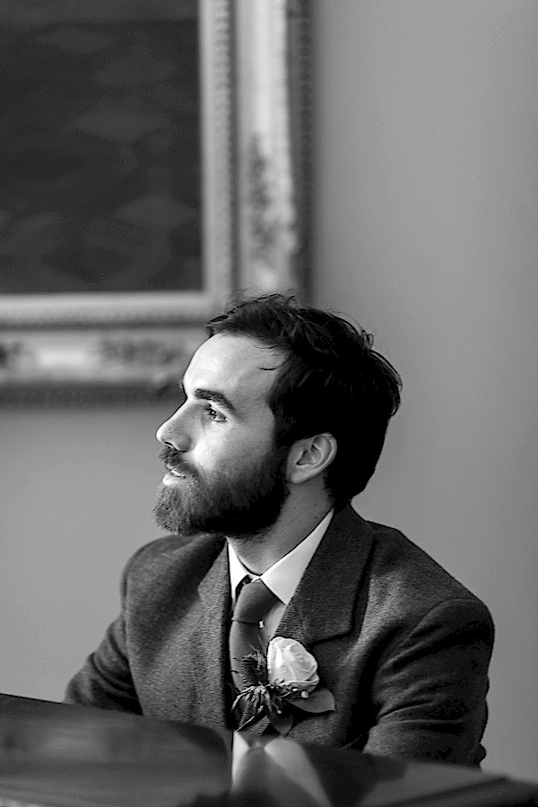 groom looking at the bride sittign behind a piano