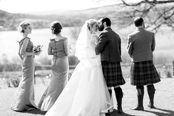 newlyweds kissing next to bridal party