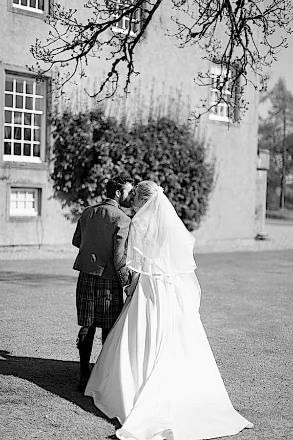 newlyweds kissing while walkng away towards boturich castle