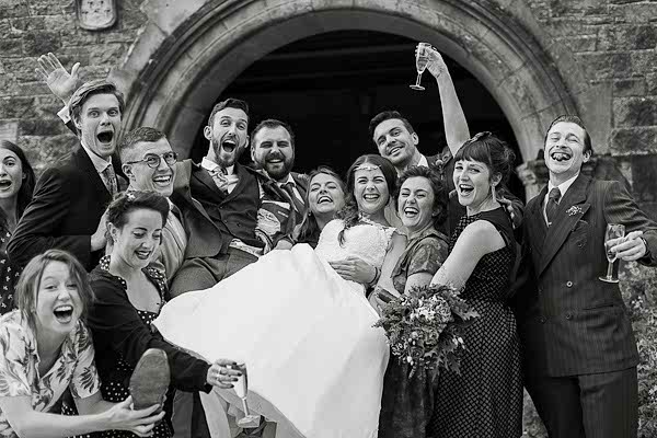 friends going crazy at wedding lifting bride and groom