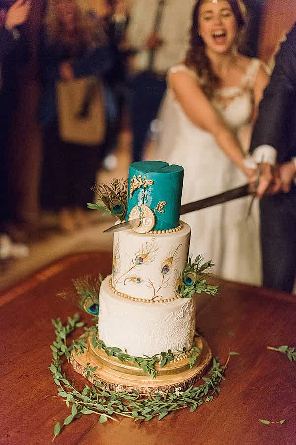 wedding cake beeing cut with a sword