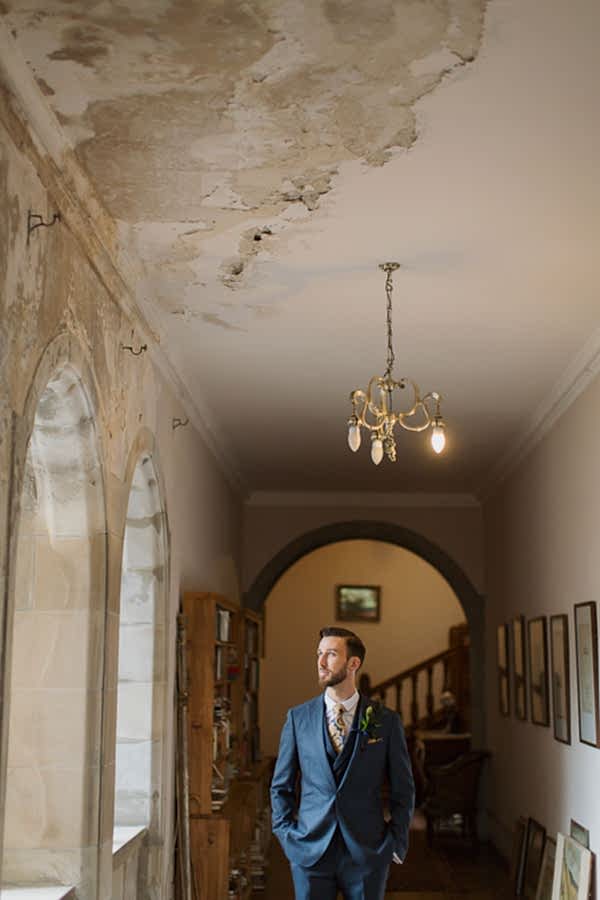 groom looking through the windo at weddign venue near glasgow scotland