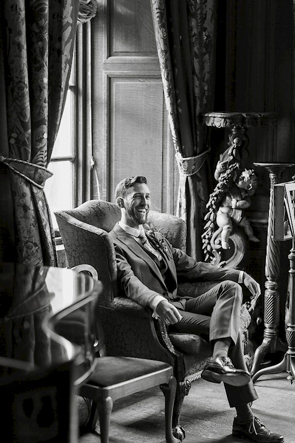 groom laughing sitting on a char at arkinglas estate hall