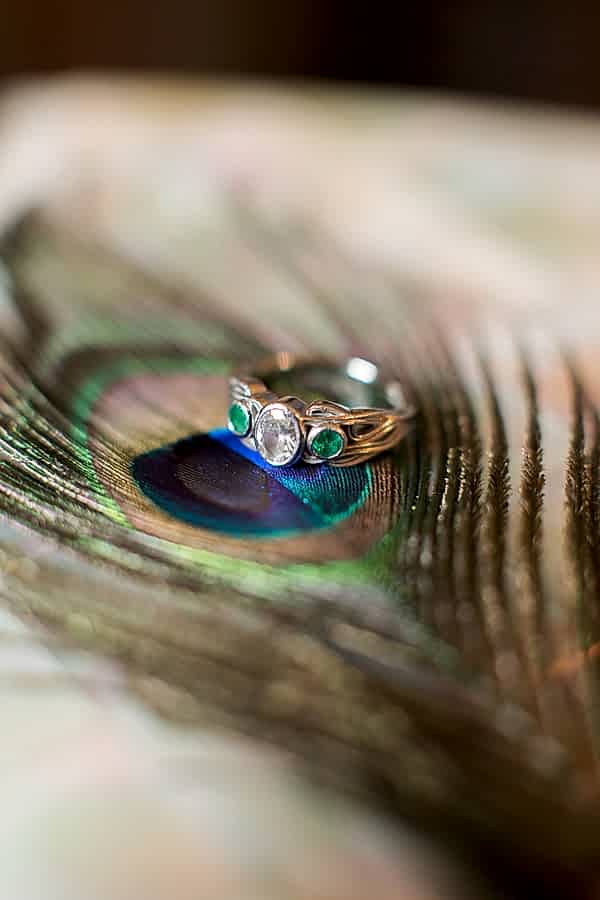 engagement ring with diamond and green stones on peacock feather