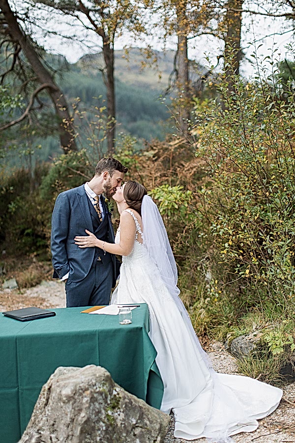 bride and groom kissing before signing paper work during ceremony