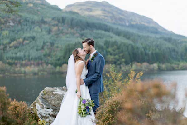 bride and groom embraced on top of a hill at loch eck near glasgow
