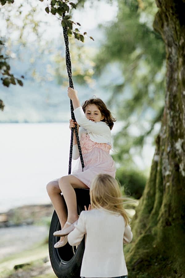 girls playin gon tire swing in the garden