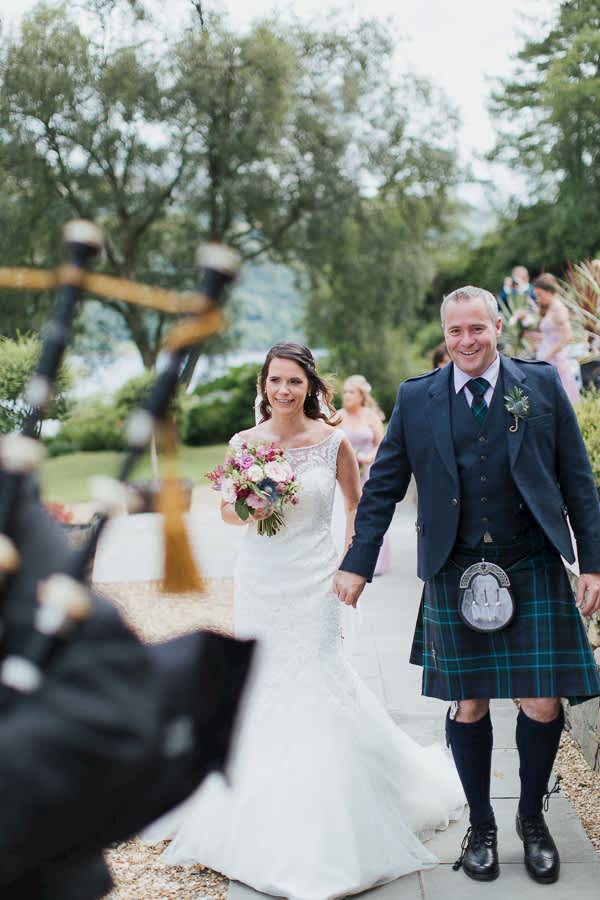 wedding photographer glasgow bride and groom leaded by piper after ceremony