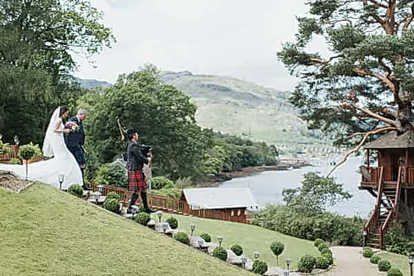 bride and groom walking down stairs with piper at the lodge on loch goil