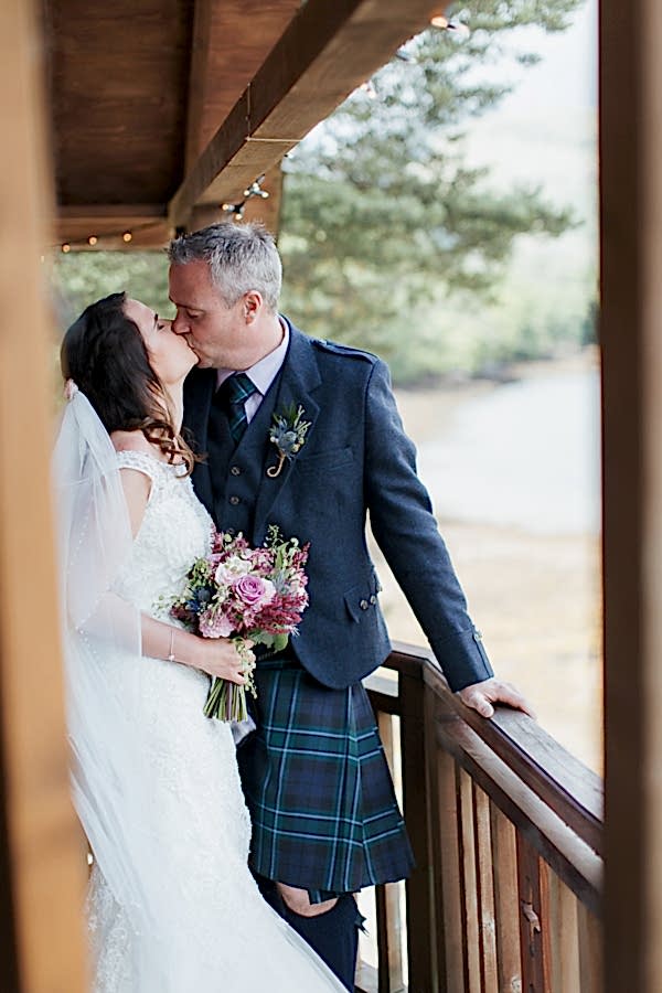 bride and groom kissing on tree house balcony scotland