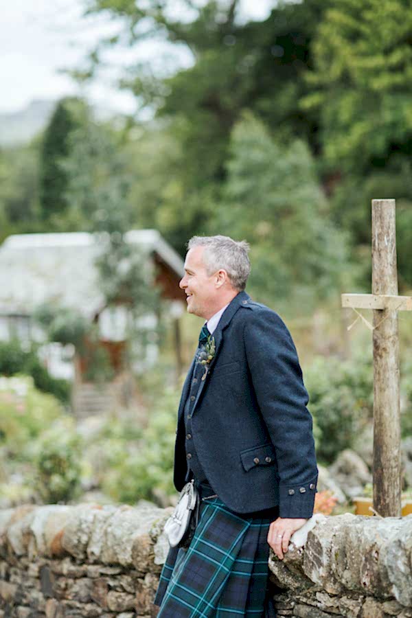 groom sitting on a brick wall