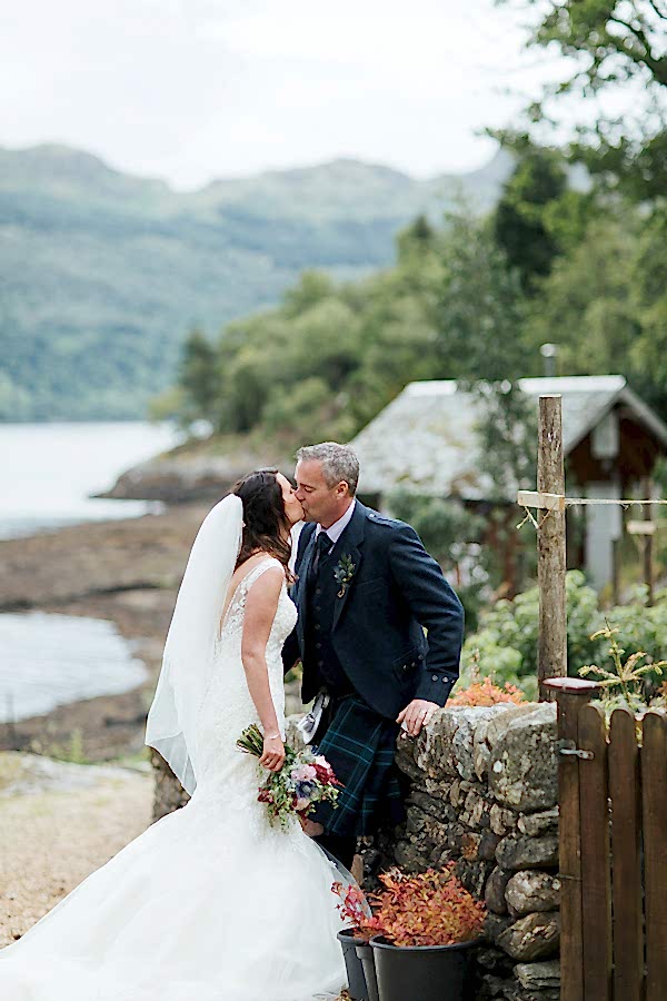 newlyweds kissing in a garden of at the lodge on loch goil