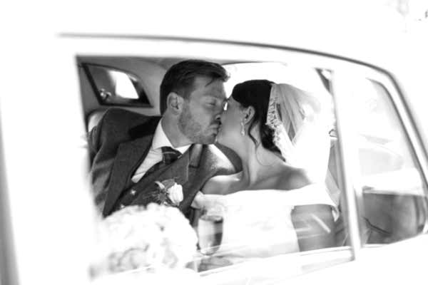 newlyweds kissing in the wedding car in glasgow