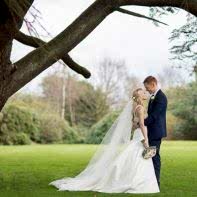 young married coupke standing under large tree mar hall wedding