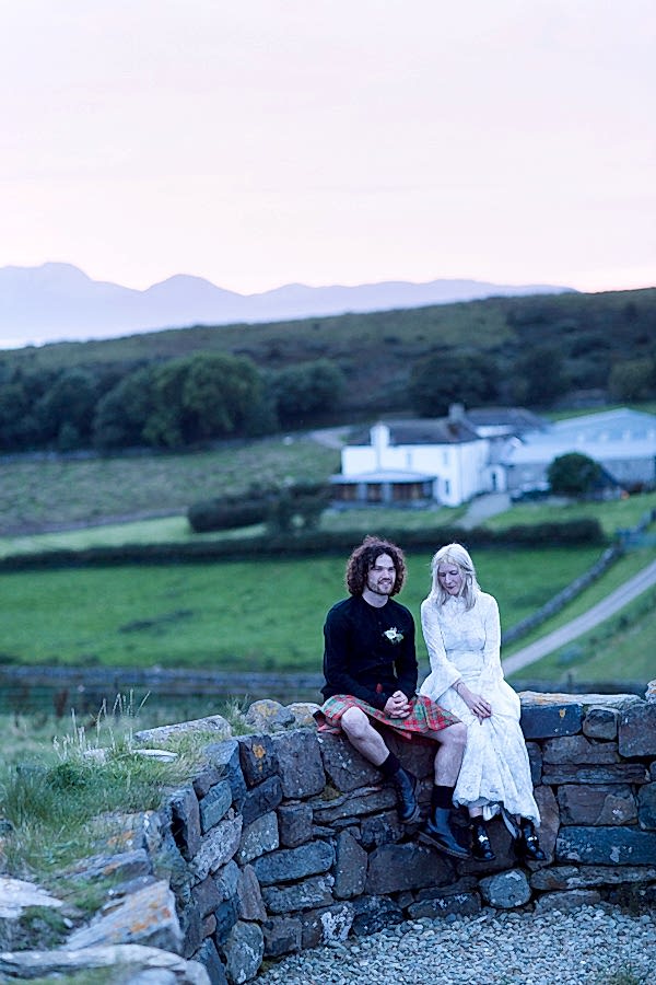 bride and groom sitting an a brick wall with view