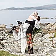 wedding photographer groom lifting bride on a rocky beach at crear scotland wedding