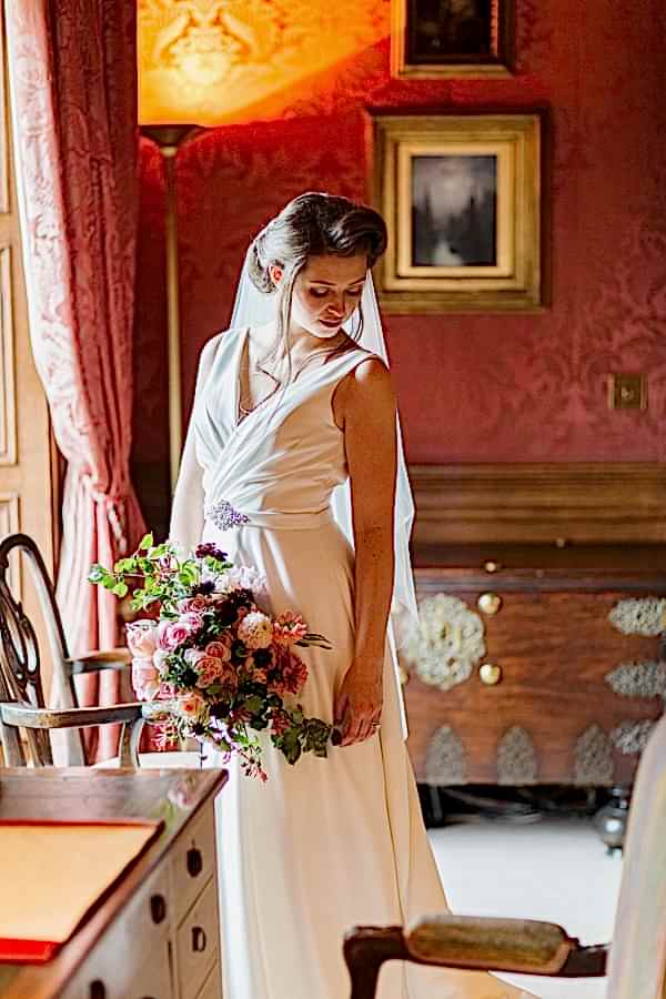 bride looking down at her dress holding flowers fotogenic of scotland