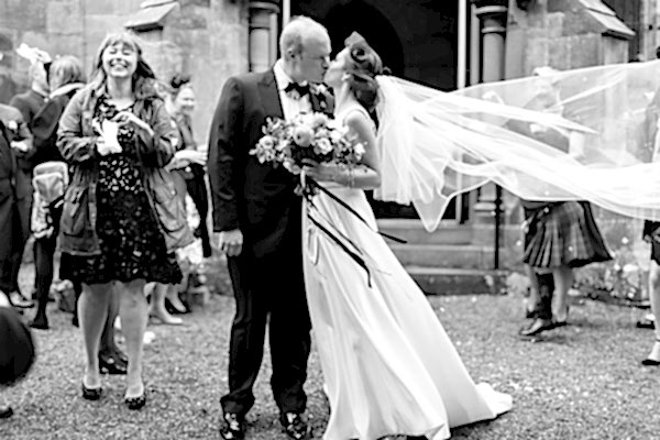 fotogenic of scotland bride and groom kissing outside church in scotland veil is lifted by wind