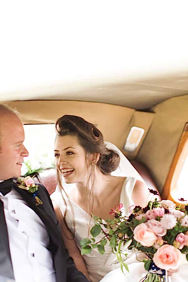 bride smiling at groom inside the wedding car