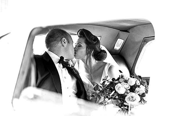newlyweds kissing inside wedding car