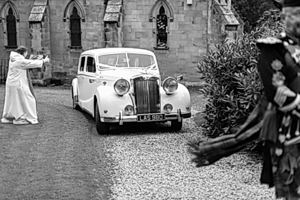 funny minister giving thumbs up while bride and groom leaving for dundas castle wedding venue leaded by piper