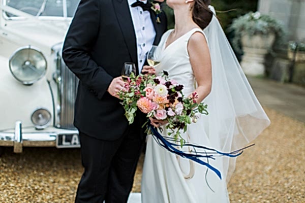 bride and groom embraced kissing holding champagine glasses