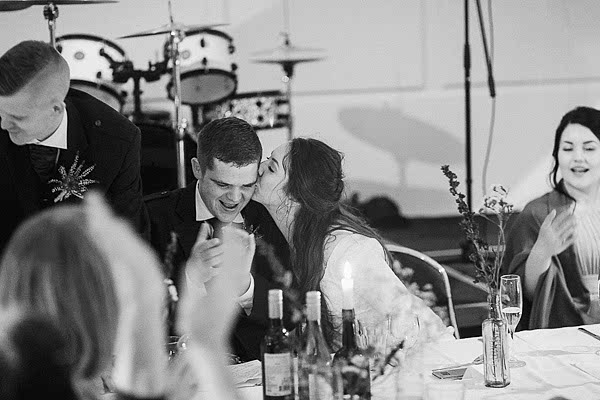 bride giving a kiss to teh groom after wedding speeches