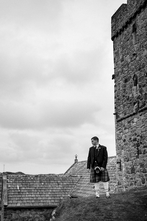 groom satanding on a hill next to the rodel church