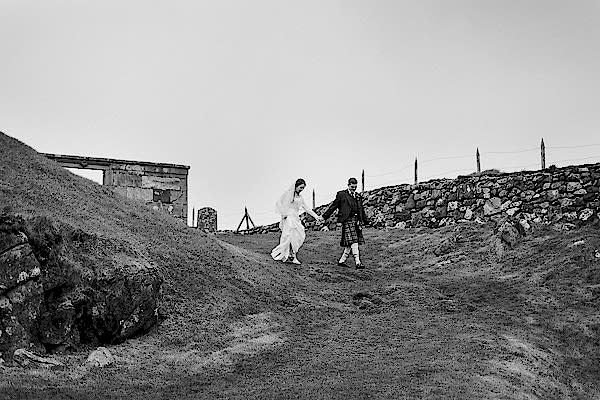bride and groom walking through field
