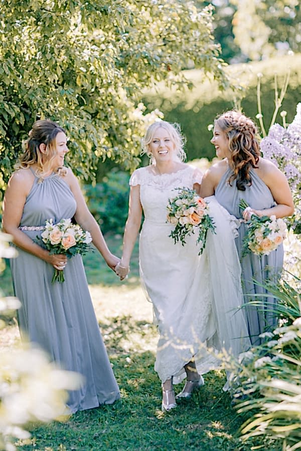 bride smiling and hloding hands with bridesmaids loch lomond 