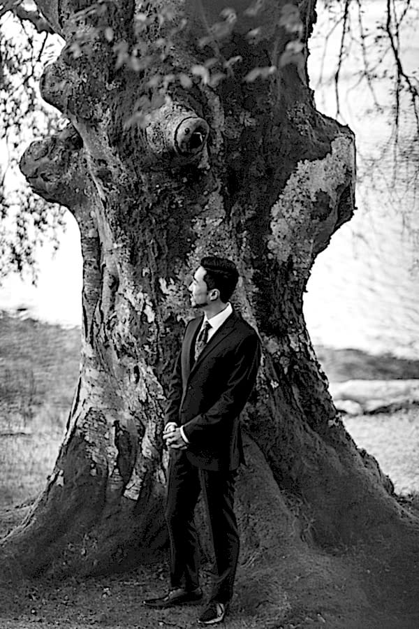groom next to a large tree