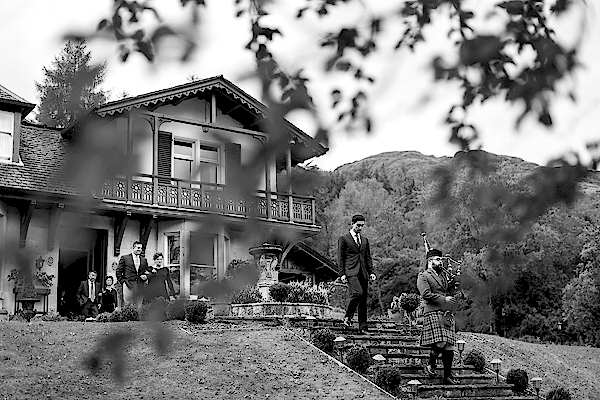 piper is leading groom and guests for tree house ceremony at loch goil